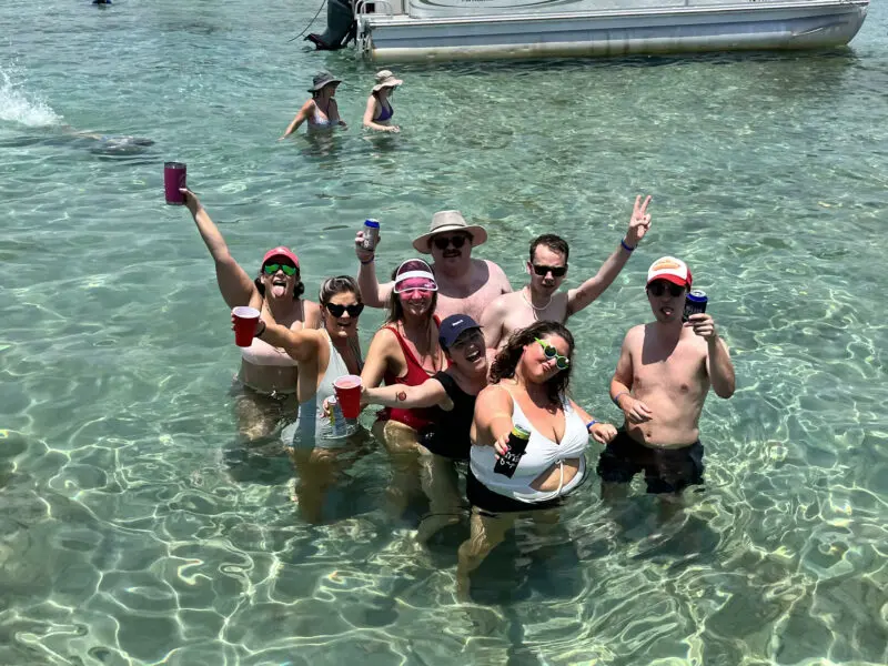 smiling friends having fun in the water at crab island with hands raised